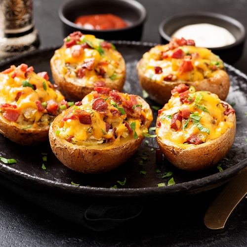 Hot baked potato topped with bacon, green onions and cheddar che